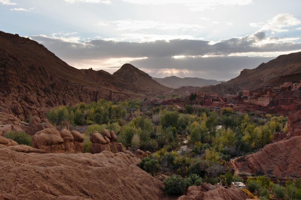 Beautiful valley in Morocco with lush greenery and rocky mountains under a twilight sky.