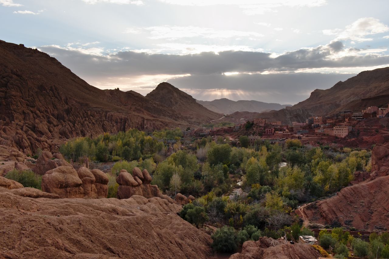Beautiful valley in Morocco with lush greenery and rocky mountains under a twilight sky.