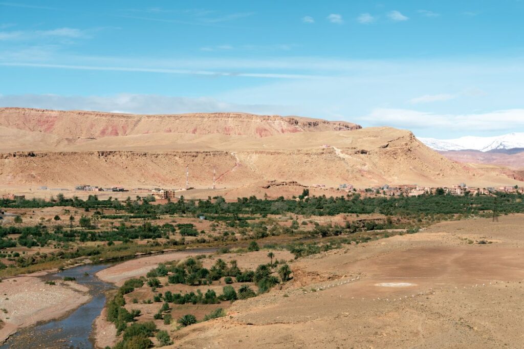 Stunning panorama of a Moroccan desert landscape with a winding river and distant mountains.