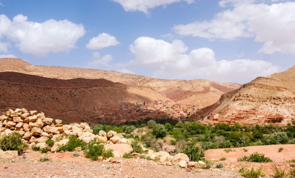 Scenic landscape of the Atlas Mountains with a traditional village under a vibrant sky in Morocco.