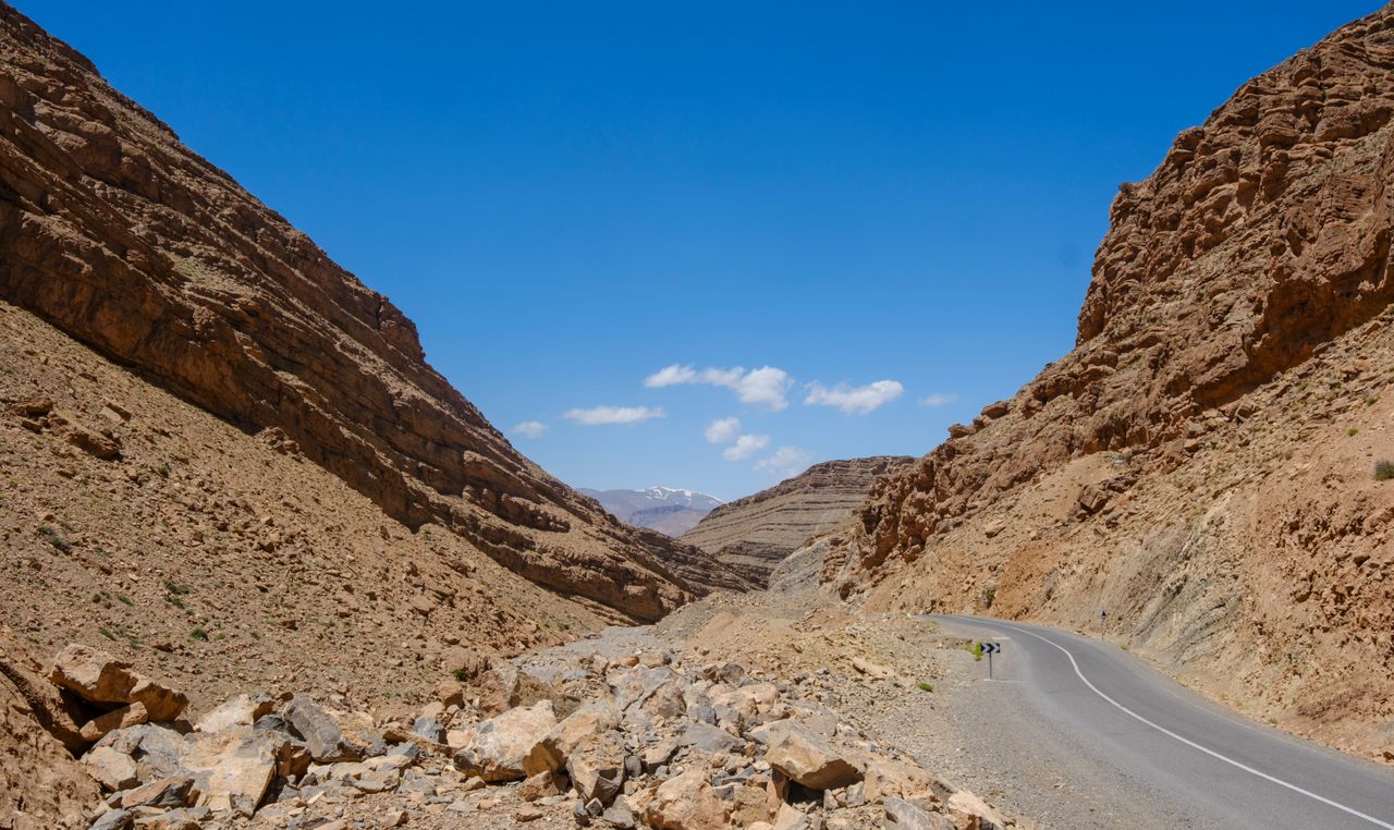A breathtaking view of a winding road through the rocky Atlas Mountains under a clear blue sky in Morocco.